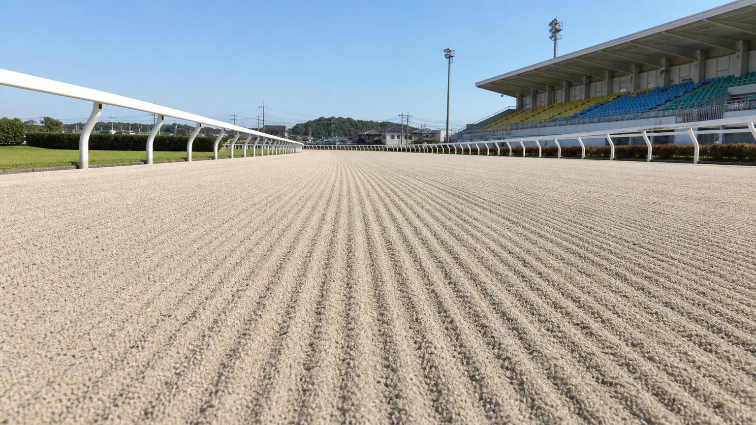 盛岡競馬場をイメージした砂のコース。レース前のハロー掛けを終えた無人の走路が、走行方向に走る細い筋を残して奥へ続いている